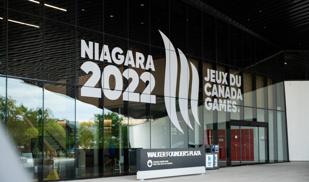 Exterior view of the Canada Games Park building featuring large ""Niagara 2022 Jeux du Canada Games"" branding on its glass facade.