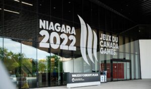 Exterior view of the Canada Games Park building featuring large ""Niagara 2022 Jeux du Canada Games"" branding on its glass facade.