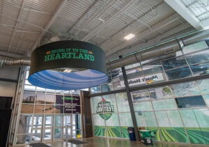 "An expansive hall features a large ""Bring it to the Heartland"" banner, an agricultural-themed Viterra entrance, and windows reflecting event branding like ""Mosaic Stadium"" and ""Grey Cup Festival."""