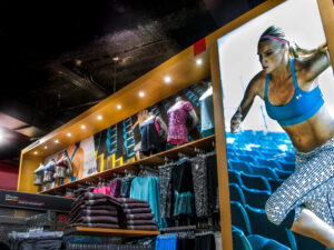"Athletic apparel store display with mannequins, clothing racks, and a large poster of female athlete Kaylyn Kyle."