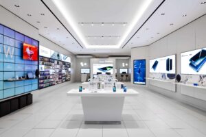 "A brightly lit, modern Samsung Galaxy retail store interior featuring mobile devices, wearables, and accessories on white displays and large digital screens."
