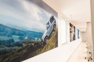 A hallway decorated with a large wall mural depicting a silver Land Rover Defender climbing a steep hill.