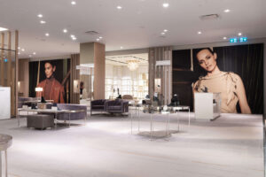 "A luxury shoe store interior features modern footwear displays, plush velvet seating, and large fashion model posters on the walls."