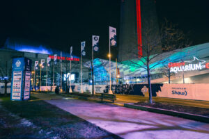 "Illuminated Rogers Centre, Ripley's Aquarium, and CN Tower at night, surrounded by Grey Cup Festival banners in Toronto."