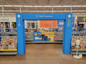 "Walmart's blue Self Checkout archway clearly indicates separate lanes for ""20+ items"" and ""Express Self Checkout."""