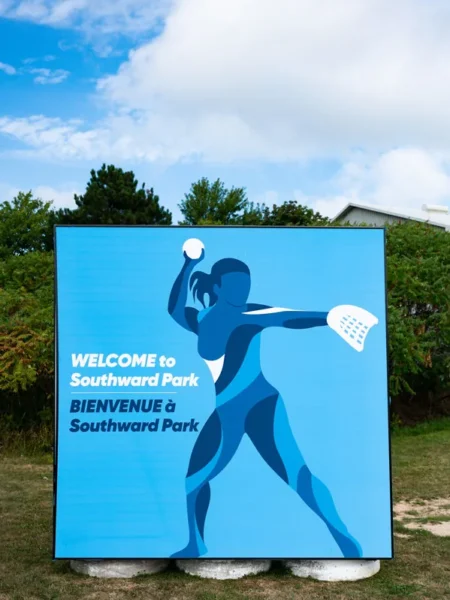 A blue outdoor sign welcomes visitors to Southward Park with a graphic of a female softball pitcher.