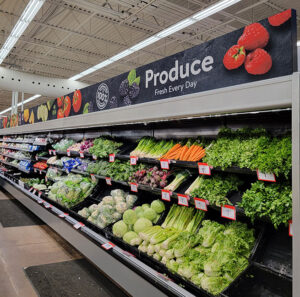 "A supermarket produce aisle brimming with fresh fruits and vegetables under a ""Produce Fresh Every Day"" sign."