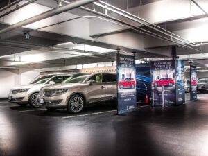 Lincoln MKX SUVs are parked in an underground garage with promotional banners for a test drive event.