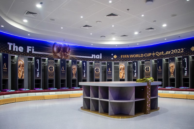 A modern FIFA World Cup Qatar 2022 locker room with trophy images on individual lockers and a central storage unit.