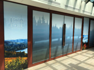 "Frosted glass doors and panels are decorated with the G7 2018 Charlevoix logo, forest silhouettes, and nature-themed art."