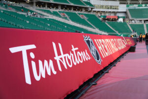 A red banner featuring the Tim Hortons logo and NHL Heritage Classic branding lines the perimeter of a stadium with empty green seats.