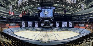 "Empty Scotiabank Arena hockey rink with ""Stanley Cup Qualifiers 2020"" displayed on the scoreboard and a large Stanley Cup logo at center ice."