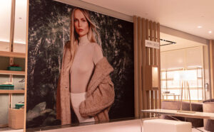 "A modern Jimmy Choo store interior with a large fashion mural of a blonde woman, shoe displays, and seating."