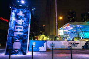 Nighttime urban scene with 104th Grey Cup festival banners and the illuminated Ripley's Aquarium.