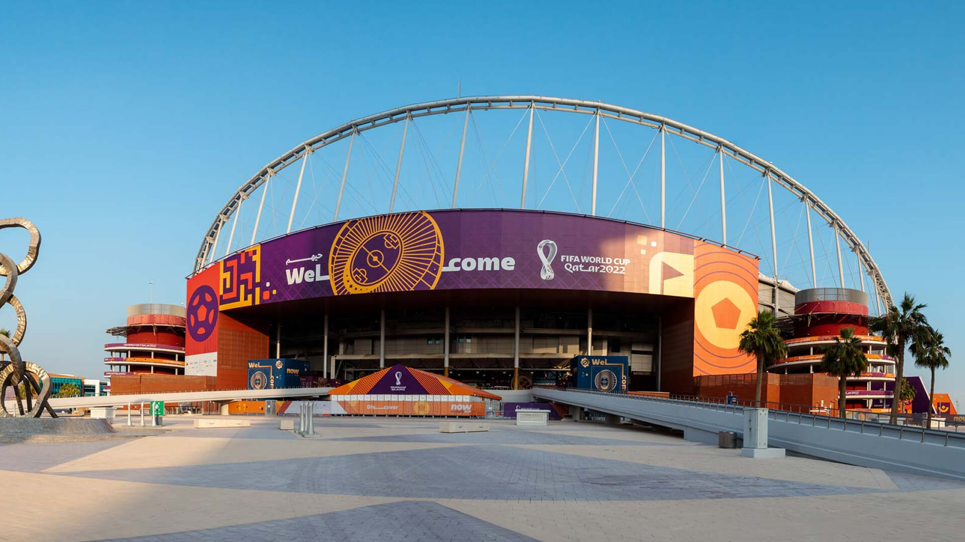 The exterior of a stadium decorated with large purple banners promoting the FIFA World Cup Qatar 2022.