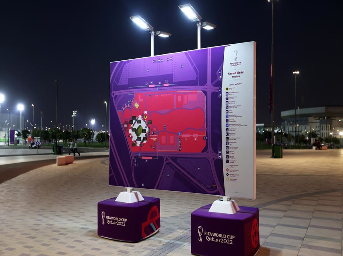 A large, illuminated map of Ahmad Bin Ali Stadium at night, flanked by FIFA World Cup Qatar 2022 branded pedestals.