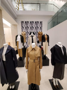 Clothing store display featuring several mannequins dressed in various neutral-toned coats and outfits.