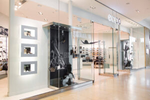 A modern ECCO shoe store with large glass display windows showcases various footwear inside.