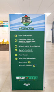 "A vertical directional sign for the 2022 Grey Cup Festival Saskatchewan, listing various event locations and services like party rooms, food vendors, and washrooms."