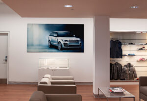 "Interior of a modern showroom with a large Range Rover image on the wall, comfortable seating, and retail displays."