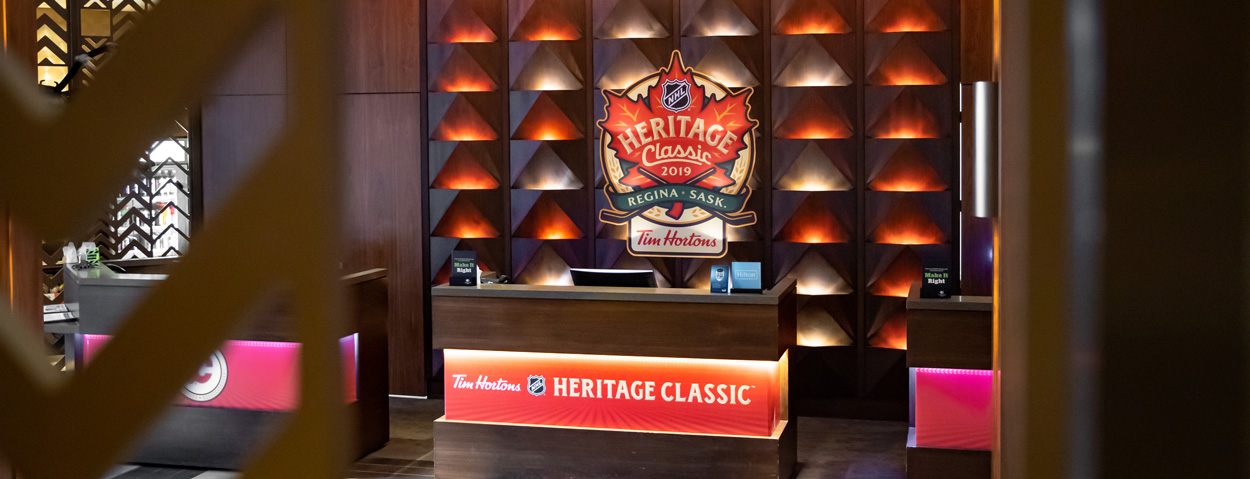 A reception area features prominent NHL Heritage Classic 2019 and Tim Hortons branding on an illuminated wall and front desk.