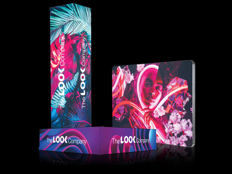 Three vibrant, backlit display units from The LOOK Company—a tall column with tropical patterns, a square panel with a portrait, and a low rectangular base—shown against a black background.