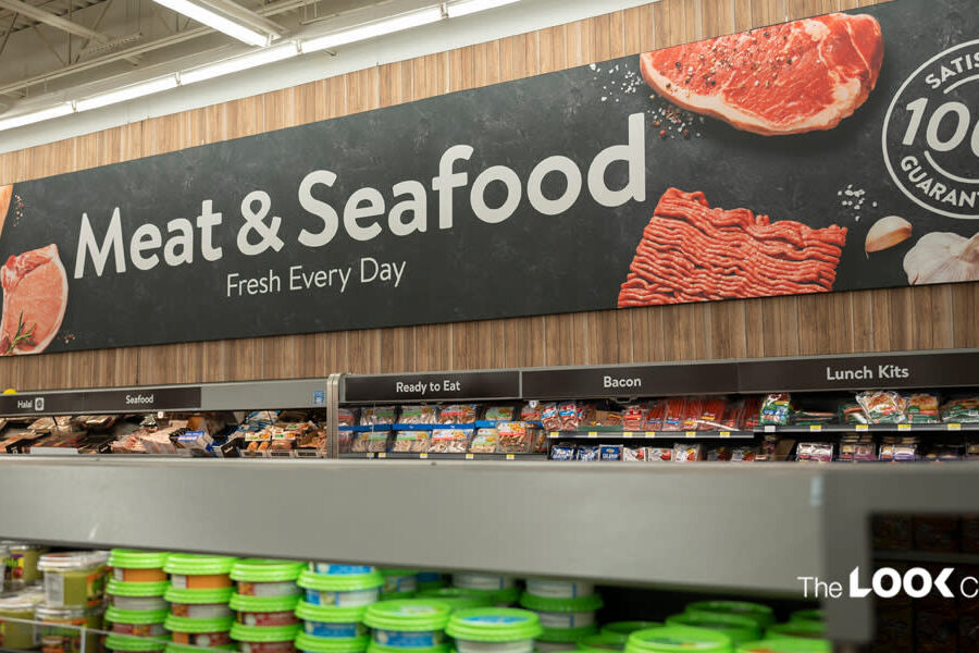 A supermarket meat and seafood aisle featuring a large sign that reads ""Meat & Seafood Fresh Every Day"" over refrigerated product displays.