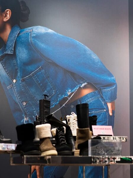 A large fashion advertisement from The LOOK Company features models in denim and a floral jumpsuit, with various boots displayed on tables in the foreground.