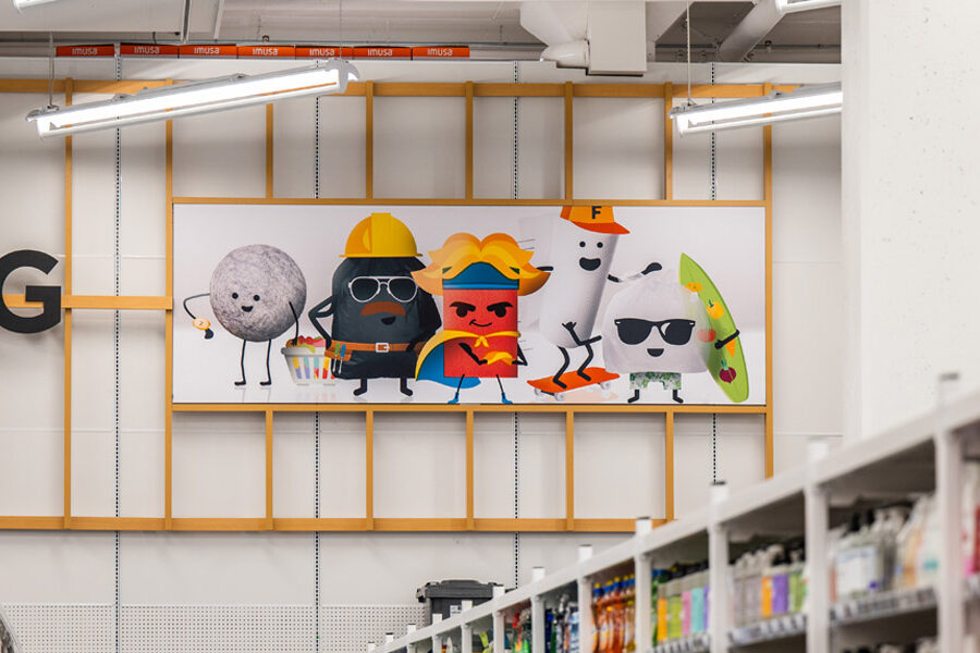 A store aisle features a large banner depicting five stylized cartoon characters above blurred shelves filled with various products.