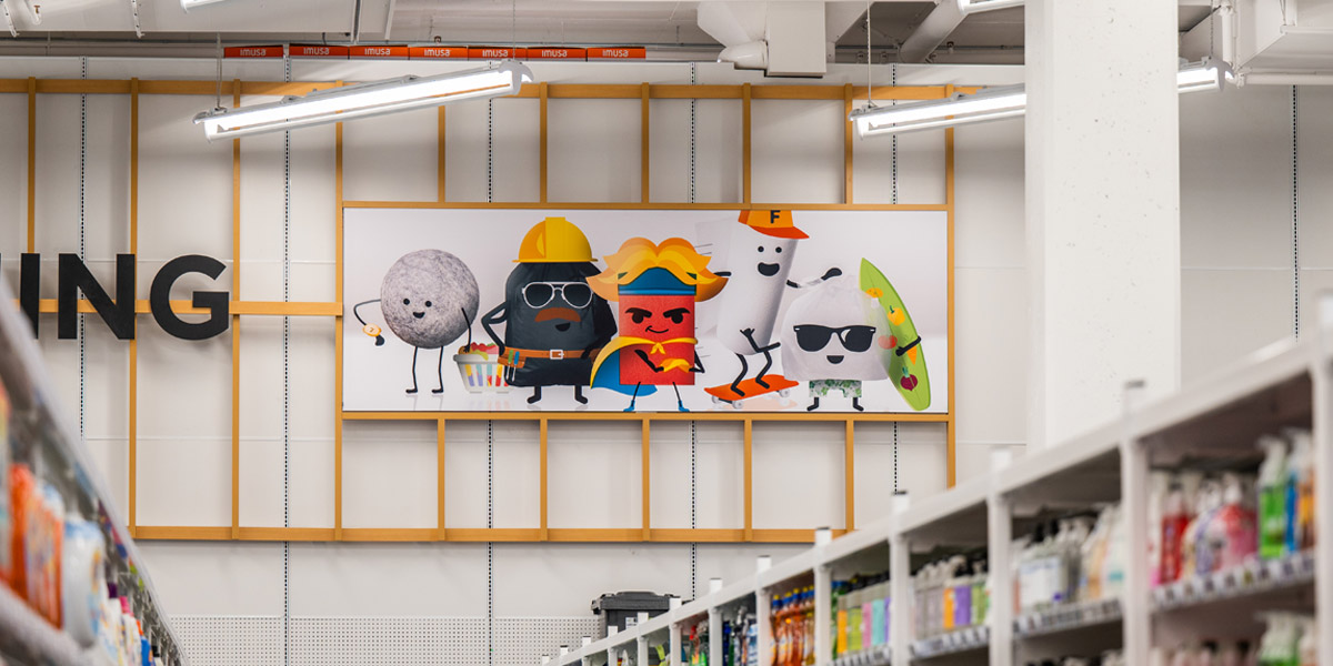 A store aisle features a large banner depicting five stylized cartoon characters above blurred shelves filled with various products.