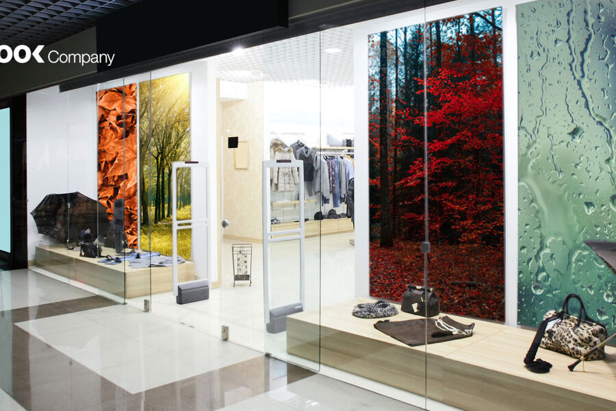 The LOOK Company storefront showcases merchandise in front of vibrant window graphics depicting autumn leaves, a red forest, and a rainy window.