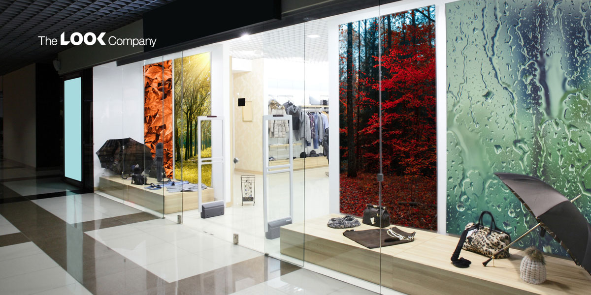 The LOOK Company storefront showcases merchandise in front of vibrant window graphics depicting autumn leaves, a red forest, and a rainy window.