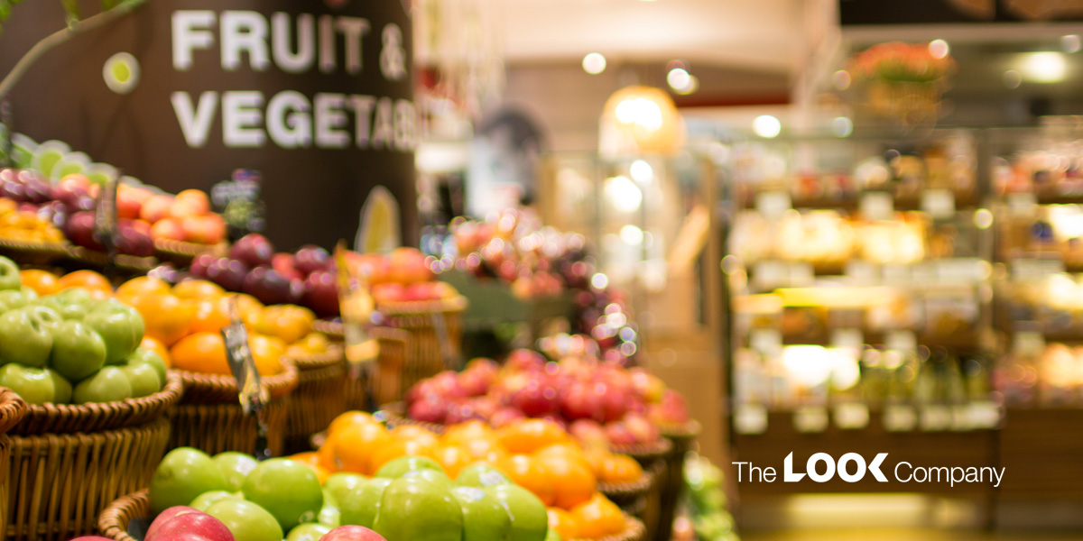 A vibrant grocery store display shows baskets brimming with green apples, oranges, and other fresh fruits, alongside a ""Fruit & Vegetable"" sign and ""The LOOK Company"" logo.
