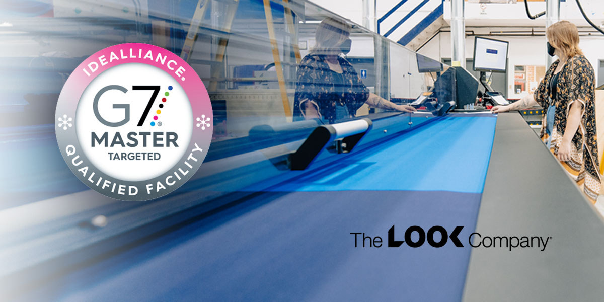 The LOOK Company's G7 Master Qualified printing facility is shown with two operators working at a large-format printer handling blue fabric.