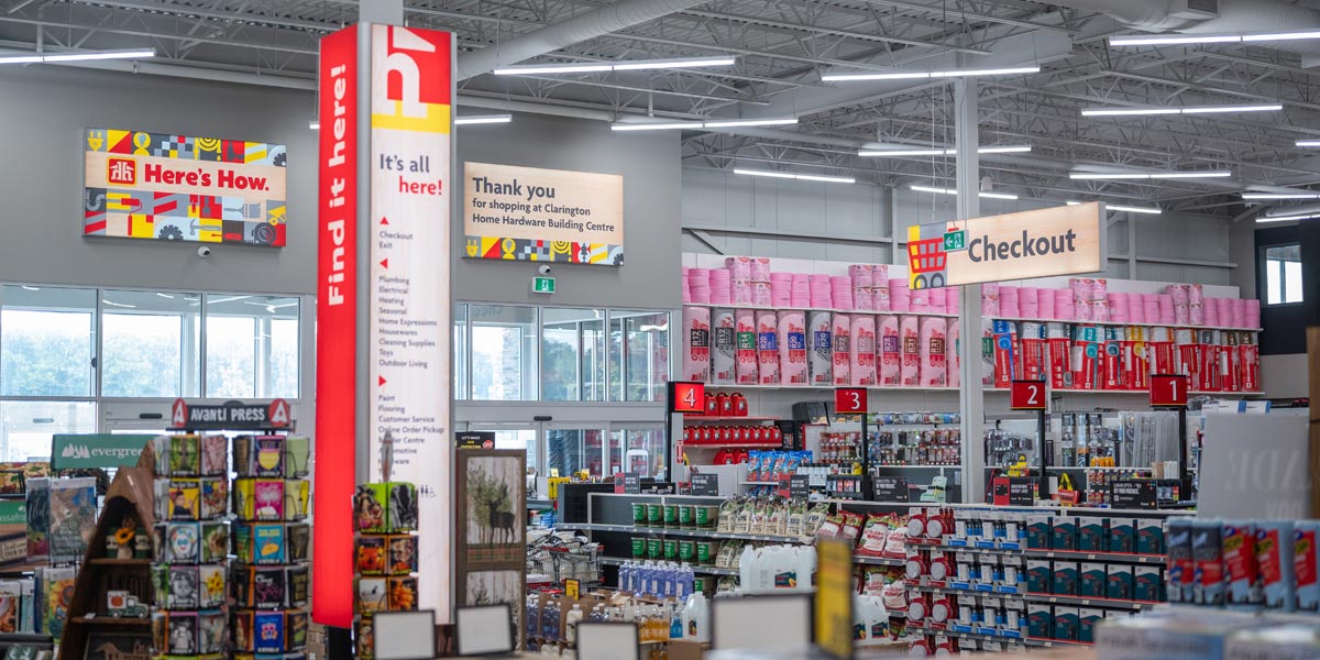 Interior of the Clarington Home Hardware Building Centre, showing prominent ""Here's How"" signage, diverse merchandise, and multiple checkout lanes.