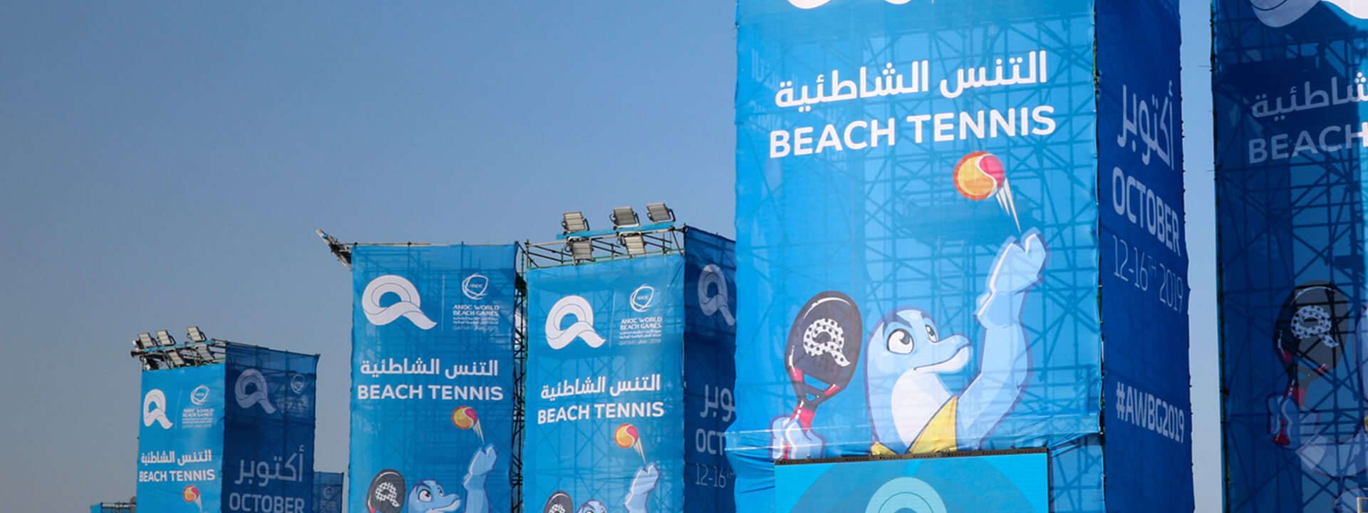 Blue banners for the ANOC World Beach Games Beach Tennis event in October 2019, featuring a dolphin mascot.