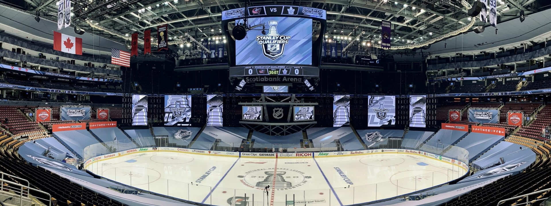 Empty Scotiabank Arena interior prepared for NHL Stanley Cup Qualifiers, featuring a jumbotron, multiple large screens, and a branded ice rink.