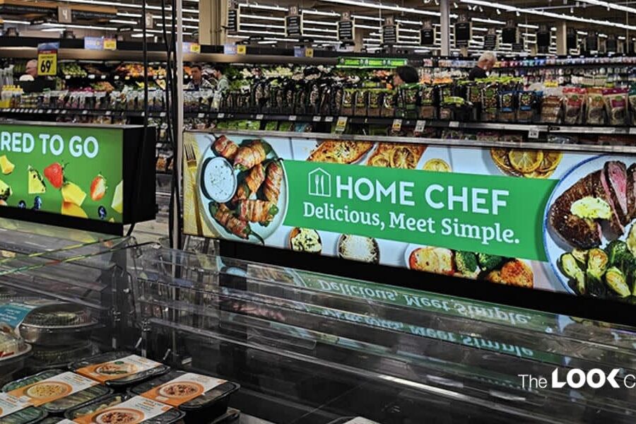 A supermarket ready-meal section features a refrigerated display case and brightly lit signs for ""Fresh Prepared To Go"" and ""Home Chef.""