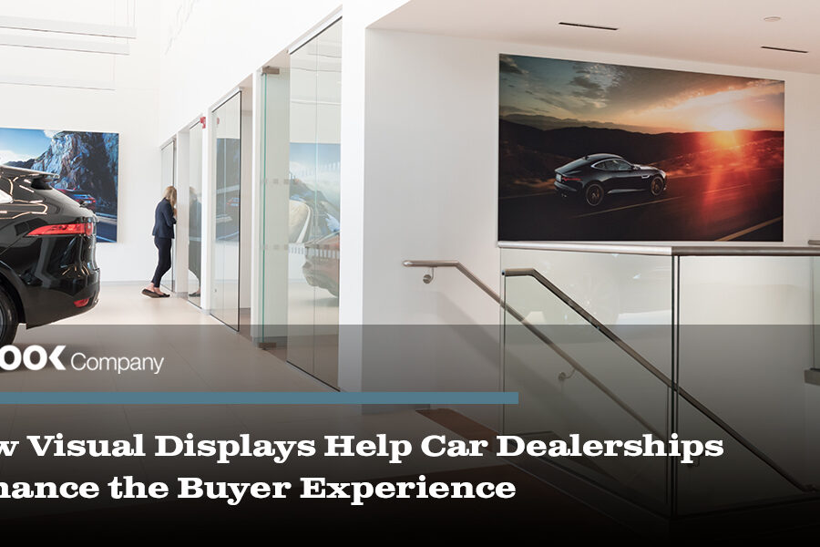 A sleek car dealership interior displaying a black SUV, a woman, and large wall graphics of cars.