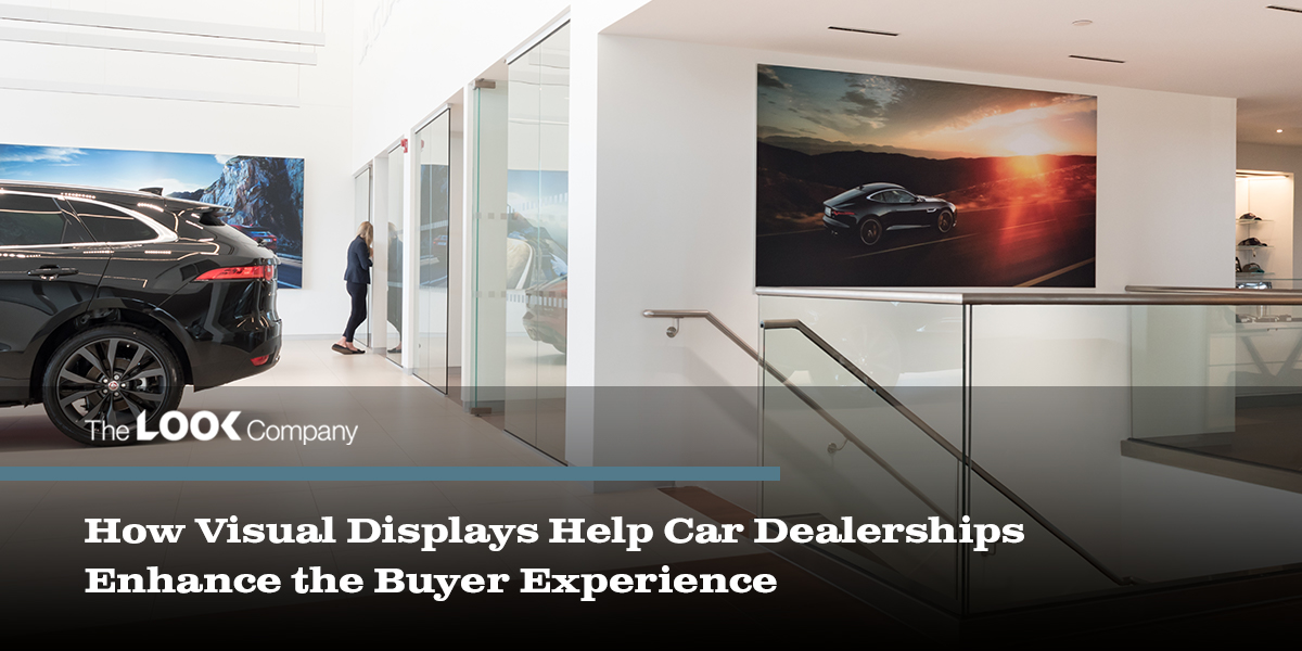 A sleek car dealership interior displaying a black SUV, a woman, and large wall graphics of cars.